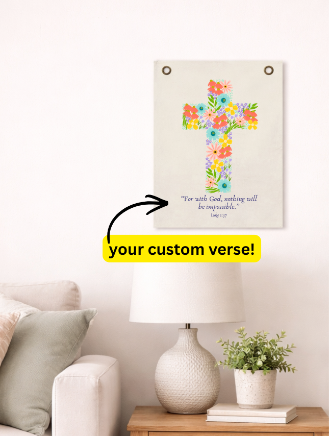 Floral cross tapestry featuring colorful flowers and a customizable verse below, displayed on a wall beside a lamp.