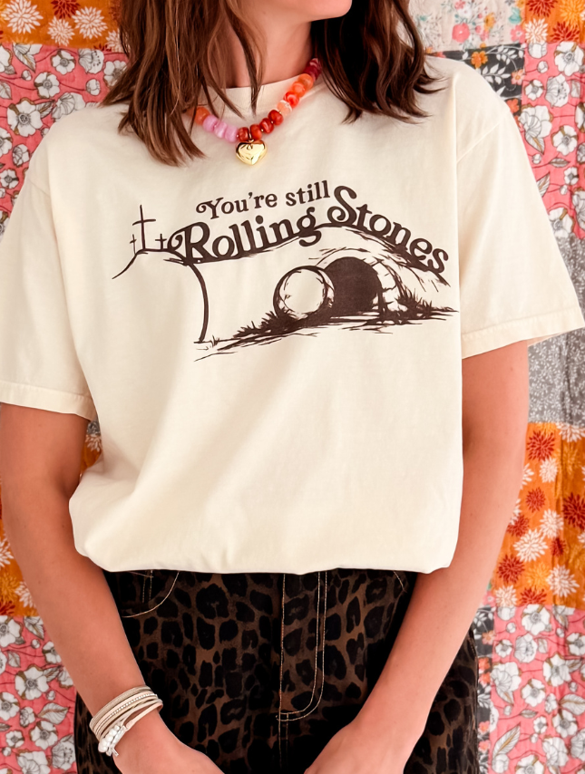 You're still Rolling Stones tee in cream with brown graphic design, worn by a model with layered necklaces and patterned b...