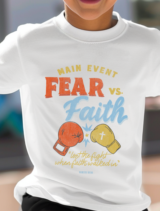 Child wearing a white t-shirt with 'Main Event Fear vs. Faith' design.