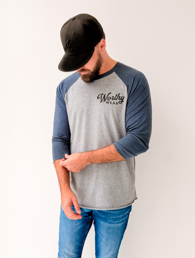 Man wearing a gray and blue baseball shirt with 'Worthy Wear' logo on a white background