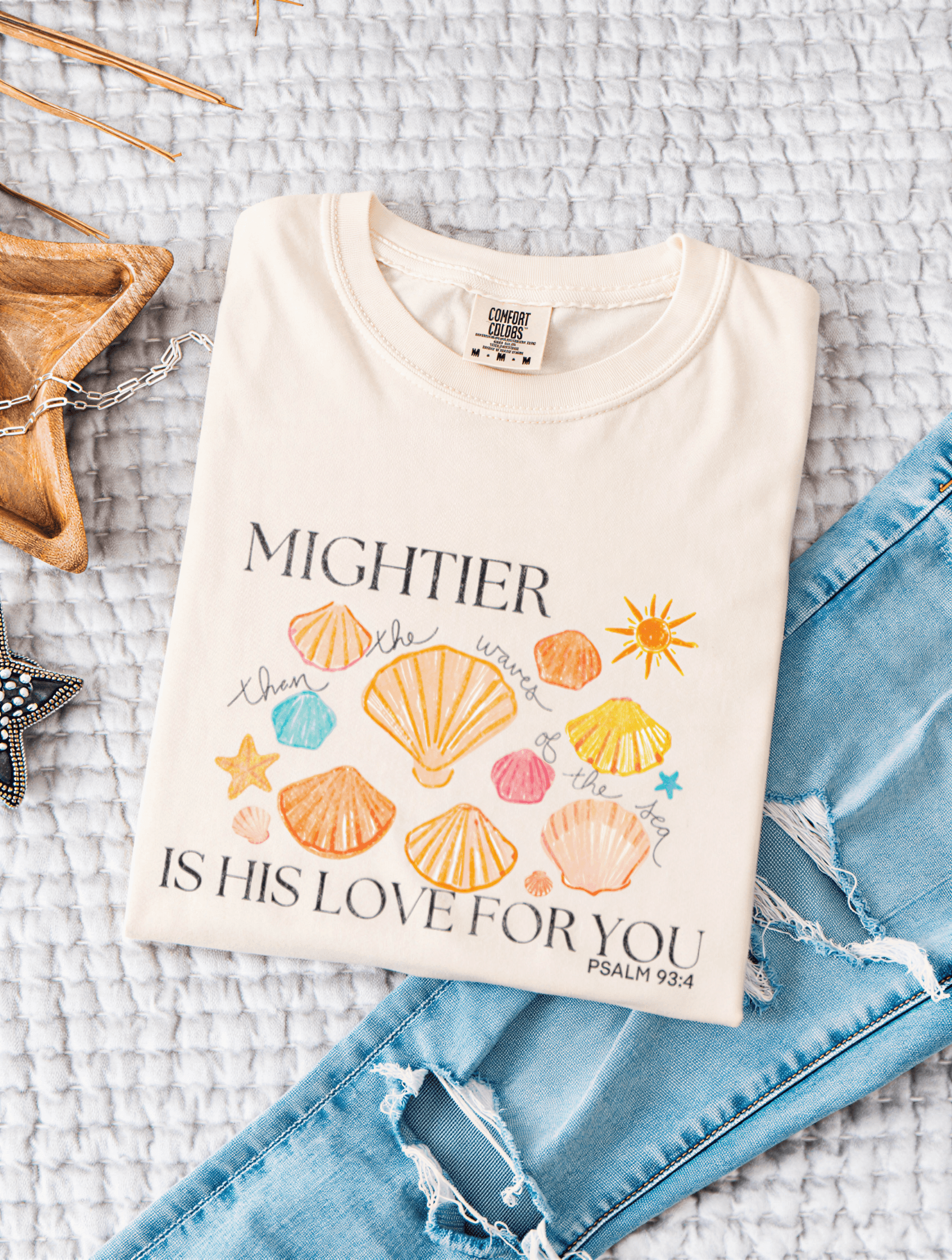 flat lay of Mightier Is His Love Tee