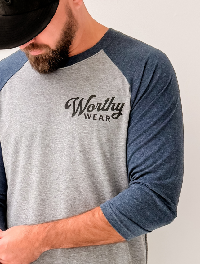 Person wearing a gray and blue long-sleeve shirt with 'Worthy Wear' logo.