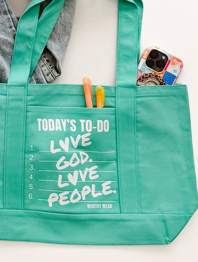 Turquoise tote bag with "Today's To-Do" list, featuring "Love God, Love People" text and pens inside.