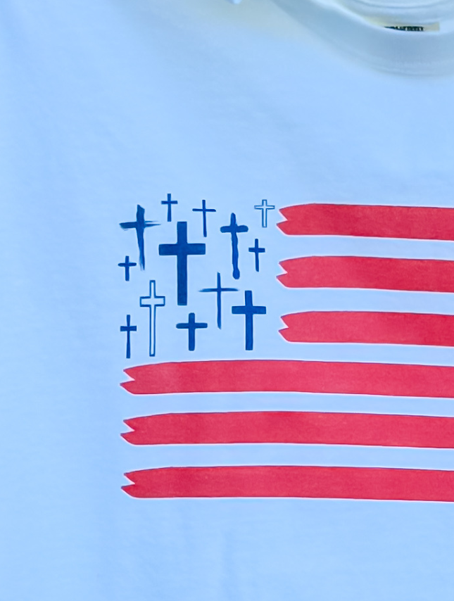 Freedom In Faith Tee featuring a white background with red stripes and blue crosses resembling the American flag.