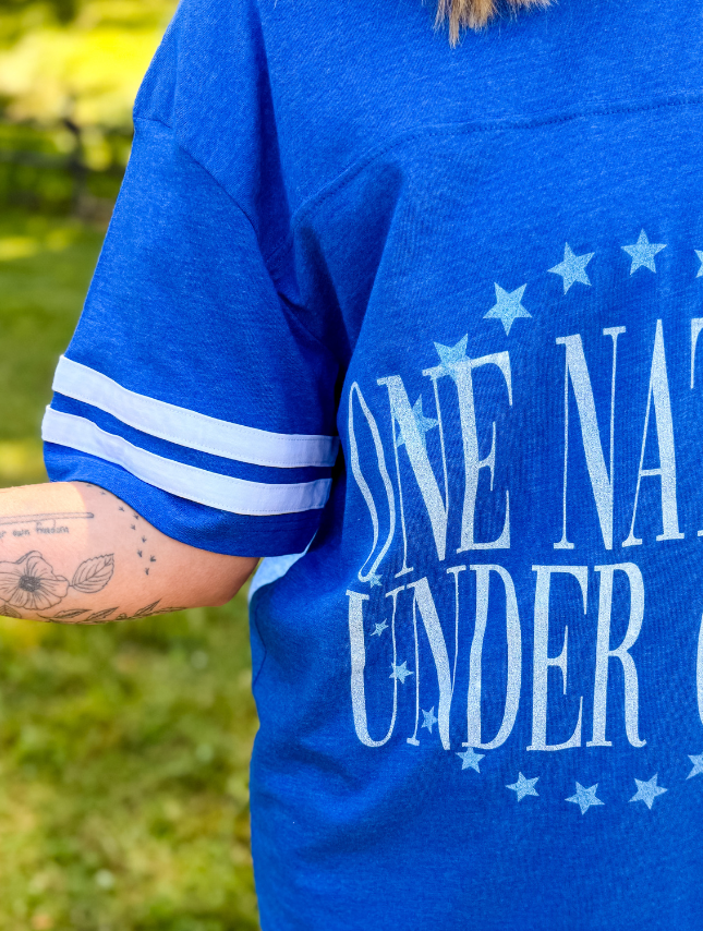 Blue jersey tee with white stripes on sleeves, featuring the text "One Nation Under God" in a bold font.