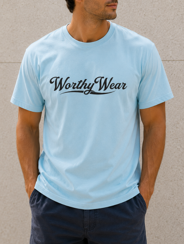 Light blue basic tee featuring "Worthy Wear" in black script, worn by a man with hands in pockets against a neutral backgr...