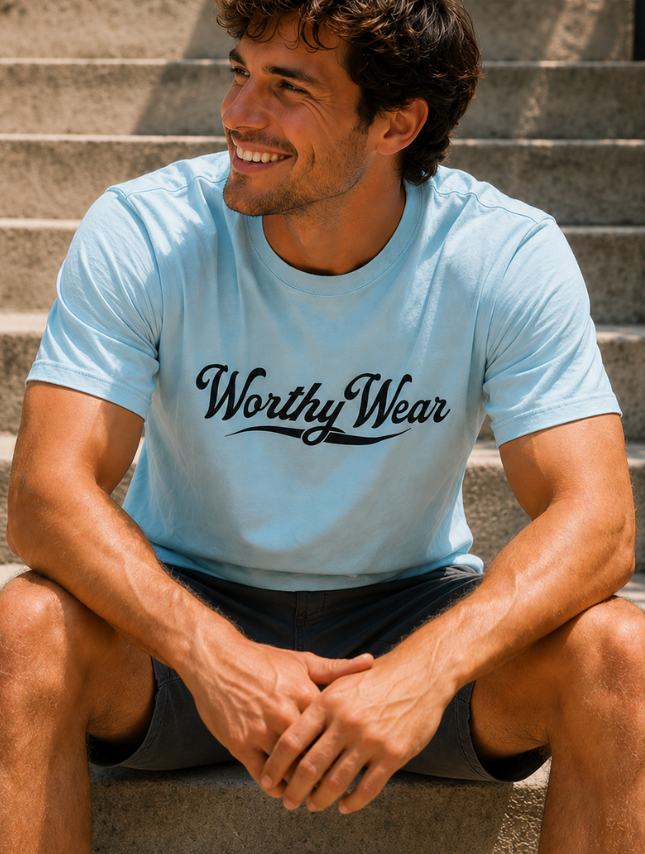 Light blue Worthy Wear basic tee with black lettering, worn by a smiling man sitting on steps.