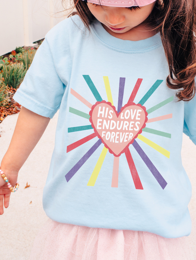 Child wearing a light blue t-shirt with a colorful heart design and text.