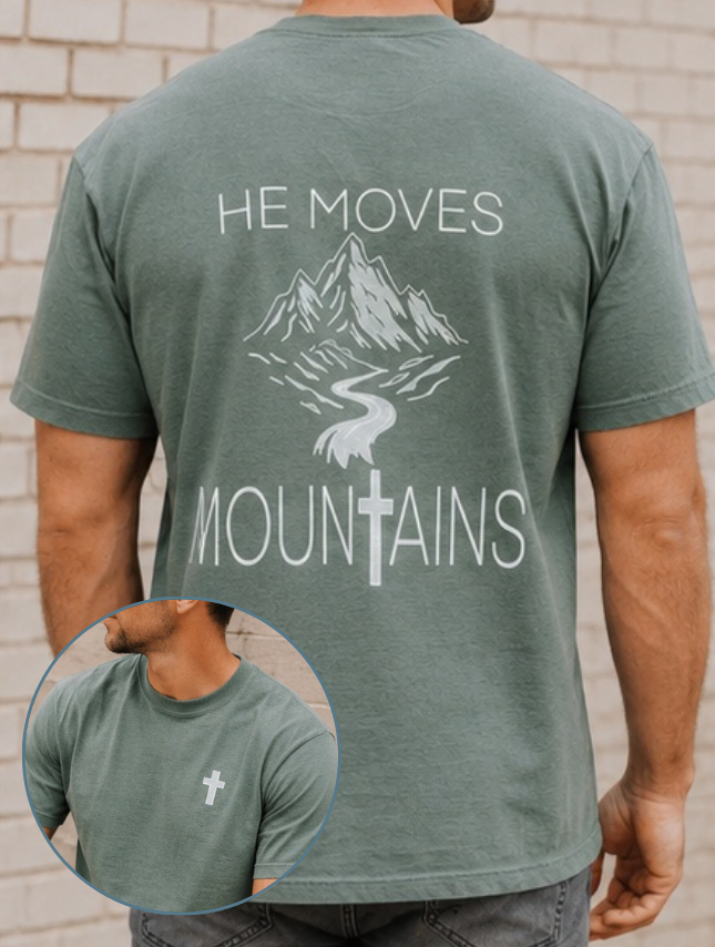 He Moves Mountains tee in moss green with mountain and cross design on the back, featuring a small cross on the front.